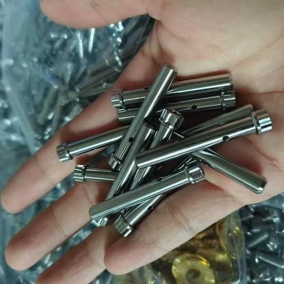 Machined broadhead ferrules in hand on the factory floor